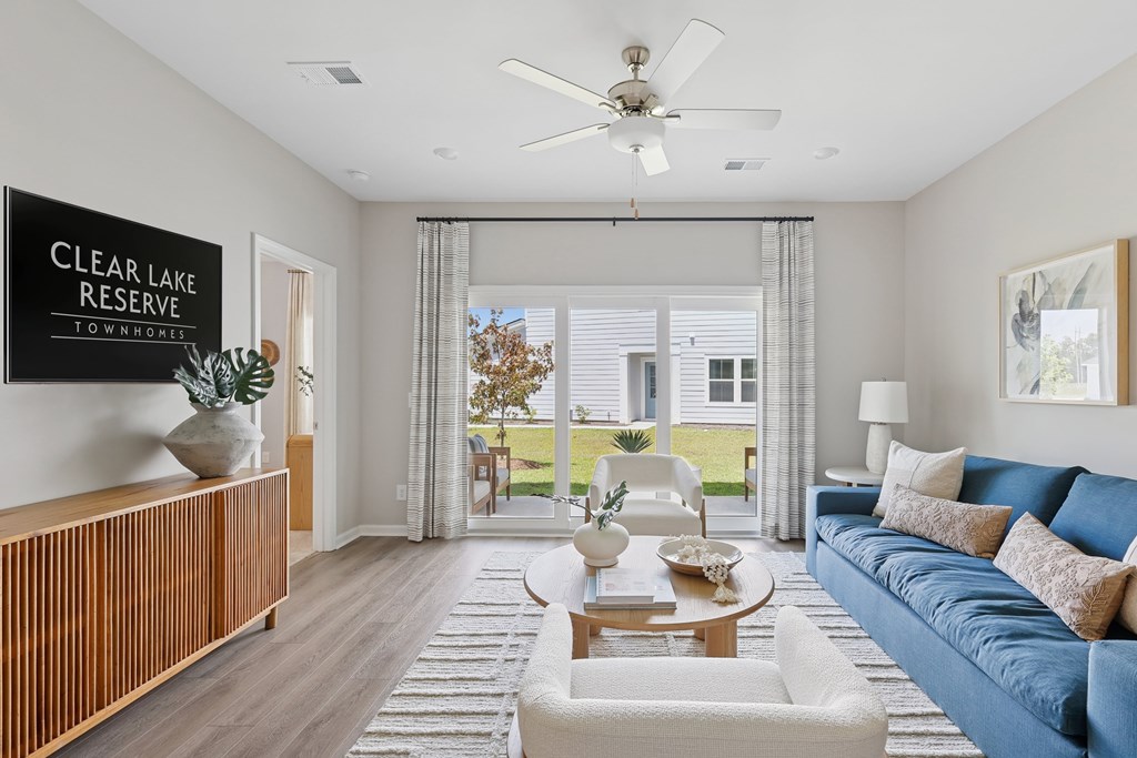 A living room with a sofa, a table, a fan, and a sign that says "Clear Lake Reserve.".