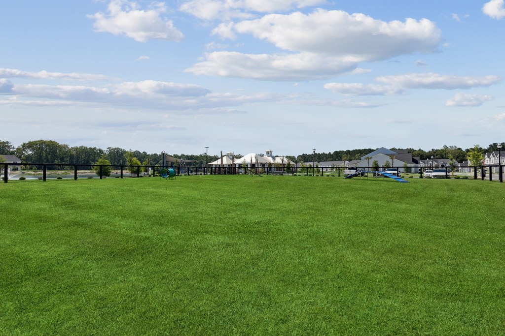 A large grassy field with a few buildings in the distance.