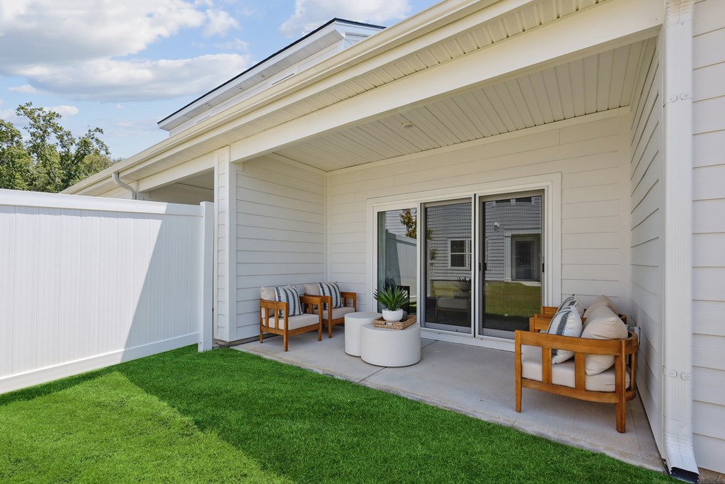 A white house with a wooden bench and a green lawn.