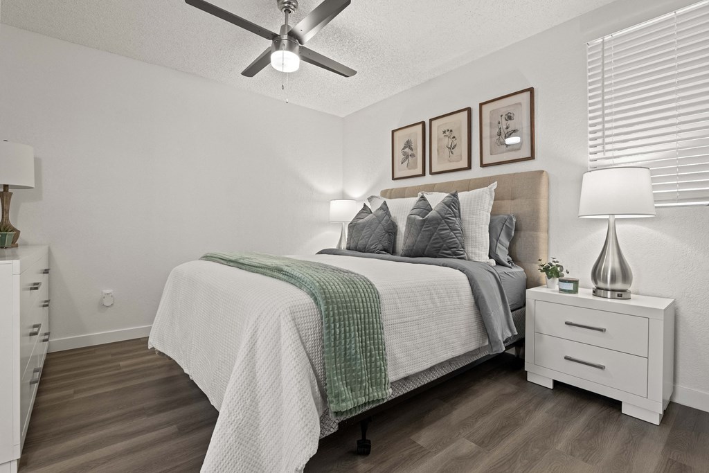 A bedroom with a bed, nightstand, and a ceiling fan.