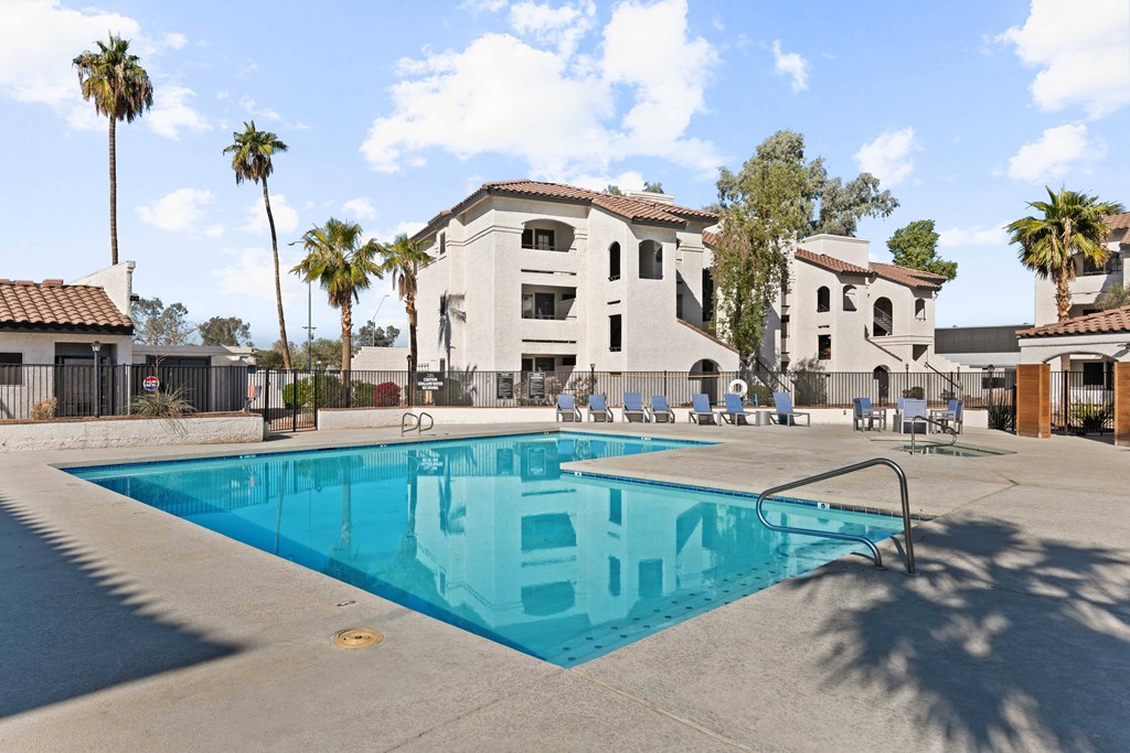 A swimming pool in front of a building with palm trees.