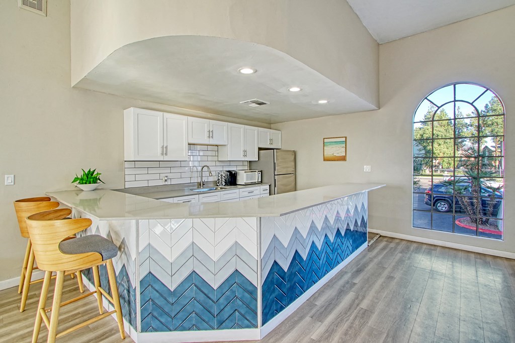 a kitchen with white cabinets and blue chevron tile