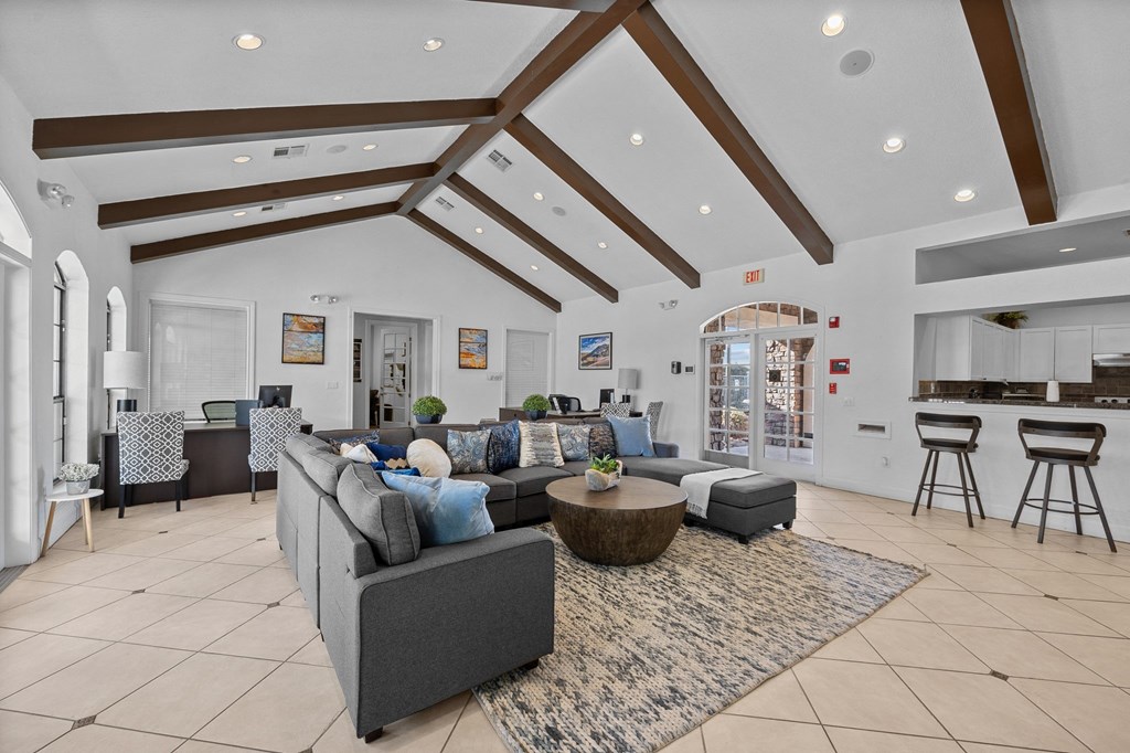 a living room with couches and a rug and a kitchen in the background