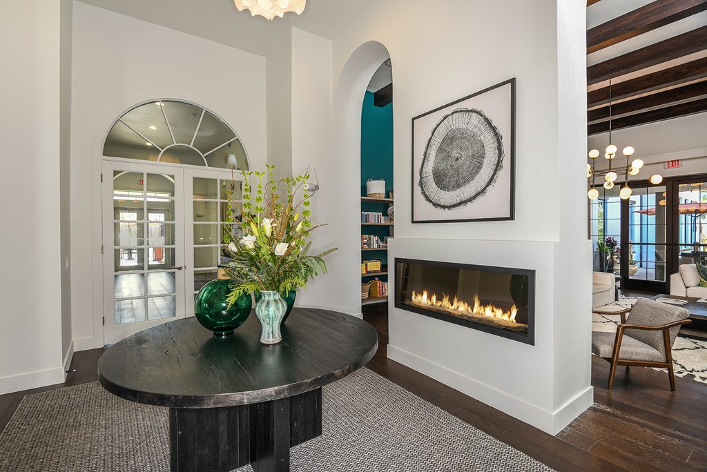 A living room with a fireplace and a round table with vases on it.