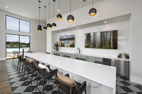 A modern kitchen with a long white counter and black and white tiled flooring.