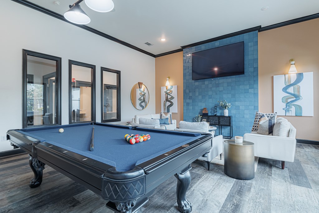 A pool table is in the middle of a room with a television and a couch.