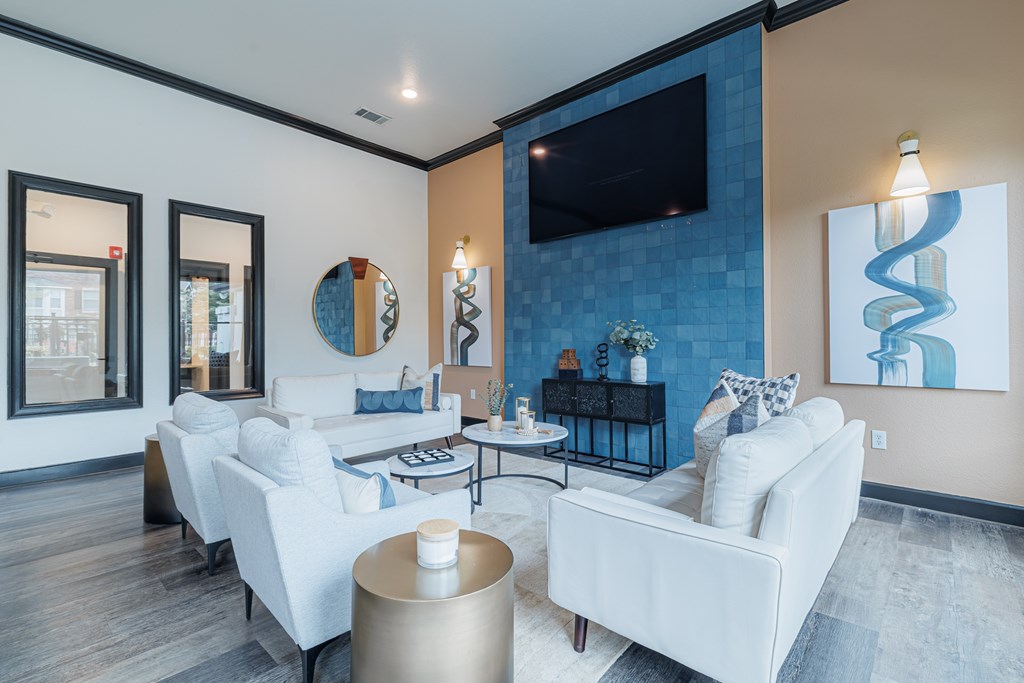 A modern living room with white furniture and a flat screen TV mounted on the wall.