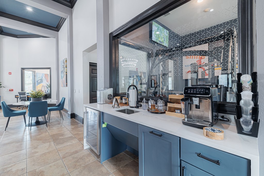 A kitchen with blue chairs and a counter with a coffee maker on it.