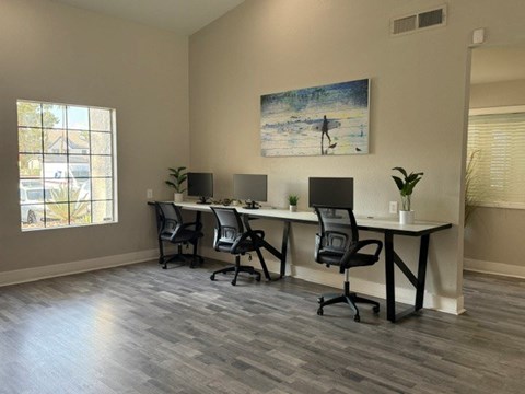 A room with a long table and chairs, a plant, and a painting of a person on a surfboard.