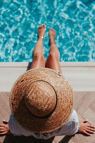 a woman lying on a poolside table with a straw hat on her head