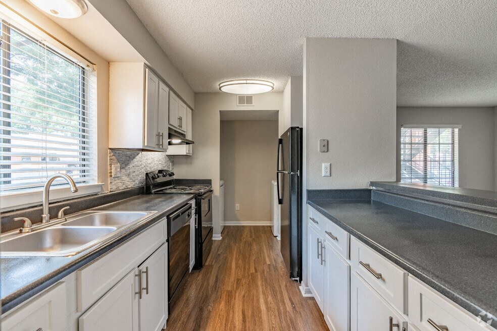 a kitchen with white cabinets and black counter tops