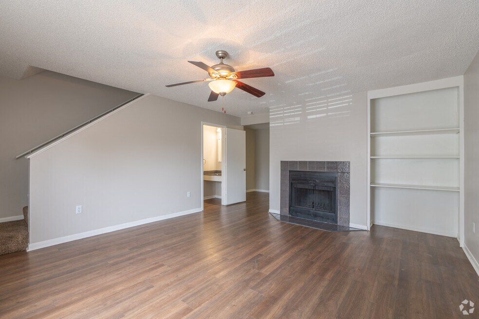 an empty living room with a fireplace and a ceiling fan