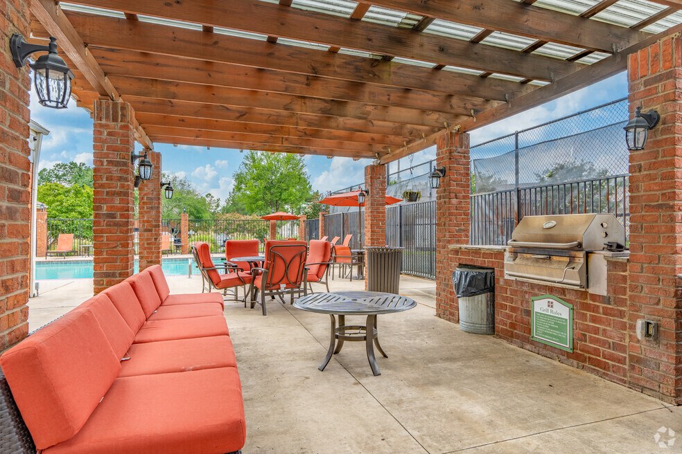 a covered patio with a grill and a table with chairs