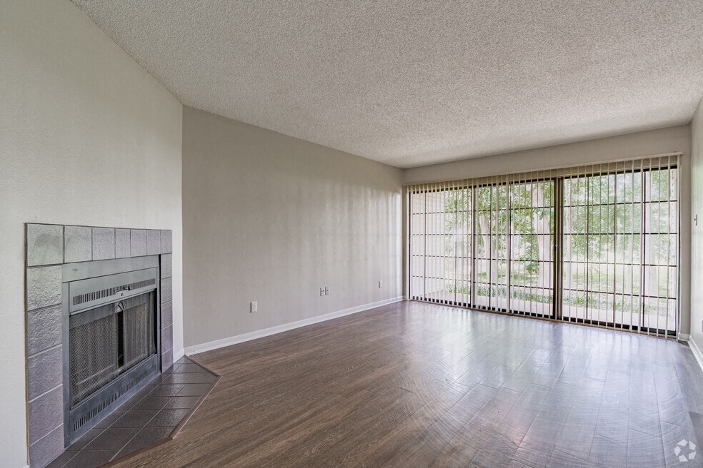 an empty living room with a fireplace and sliding glass doors