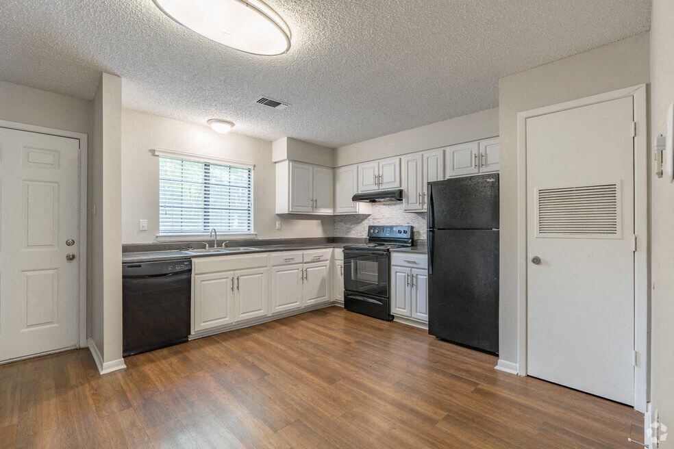 an empty kitchen with white cabinets and black appliances