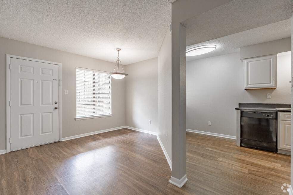an empty living room and kitchen with a white door