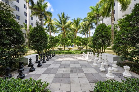 a large chess set in the middle of a courtyard with palm trees