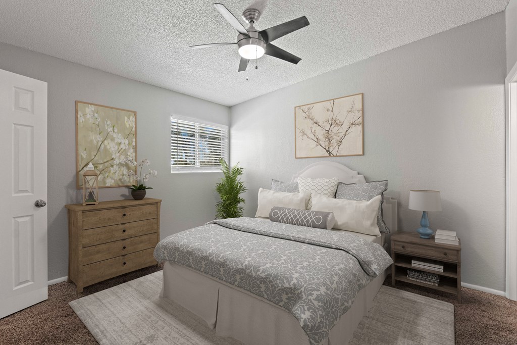 A bedroom with a bed, dresser, and ceiling fan.