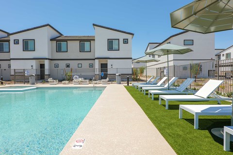 A swimming pool is surrounded by sun loungers and umbrellas.
