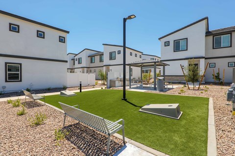 A white building with a black roof and a green lawn in front.