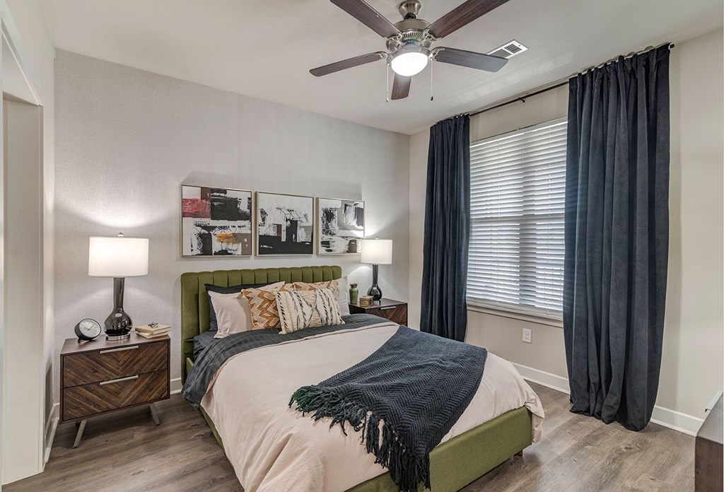 A bedroom with a bed, nightstands, and a ceiling fan.