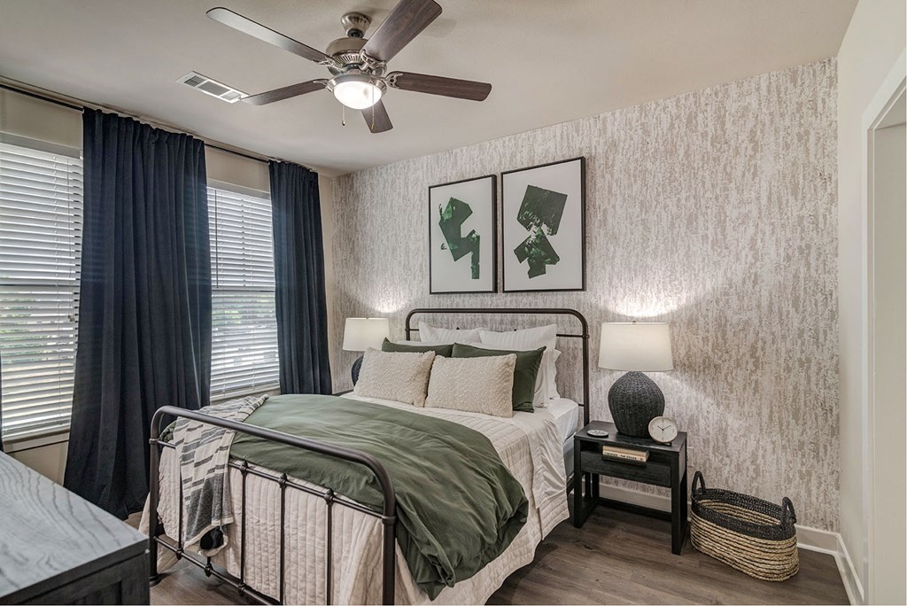 A bedroom with a bed, nightstand, and two pictures on the wall.