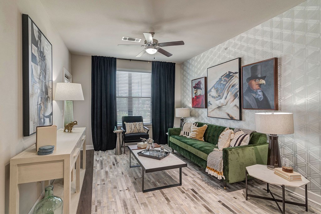 A living room with a green couch and a ceiling fan.
