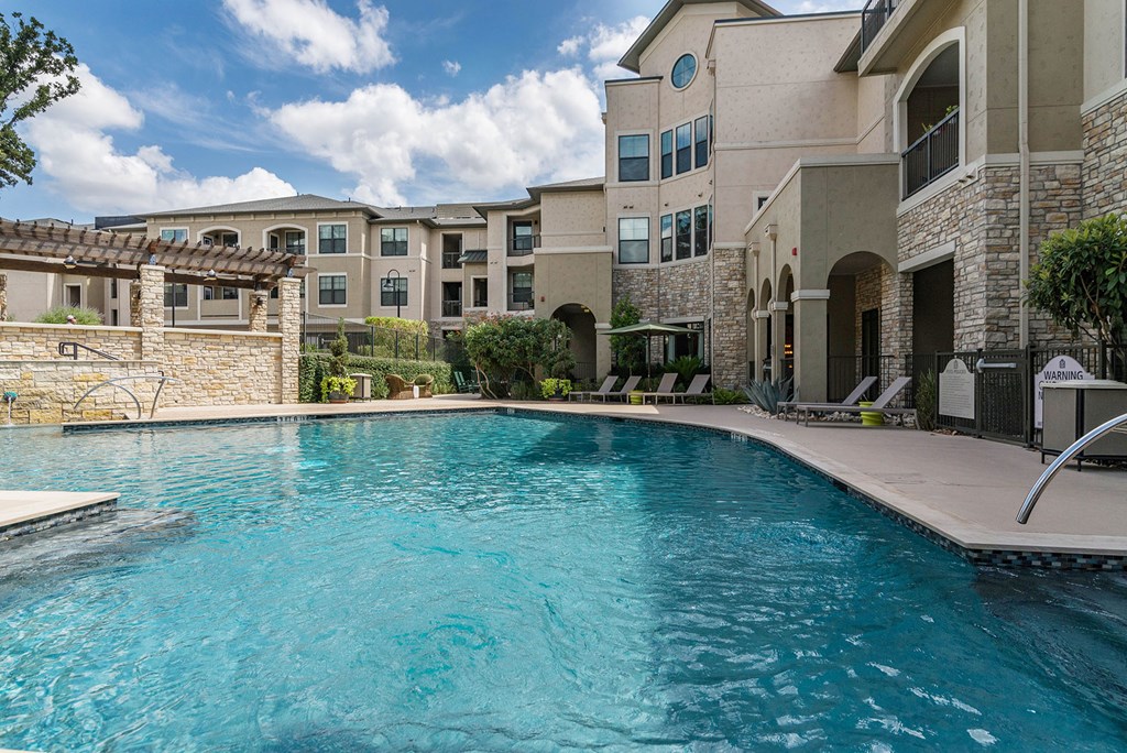 A swimming pool in front of a building with a stone wall.