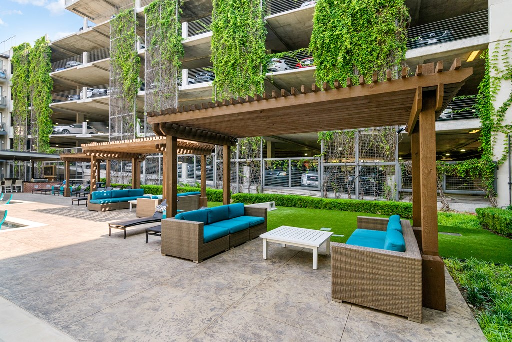 A patio area with a wooden pergola and woven furniture.