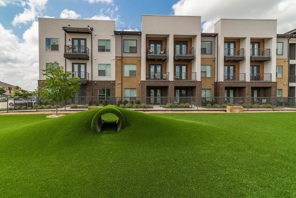 an open field of grass in front of an apartment building