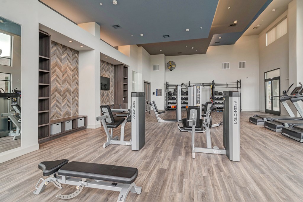 a gym with cardio equipment and weights on the floor