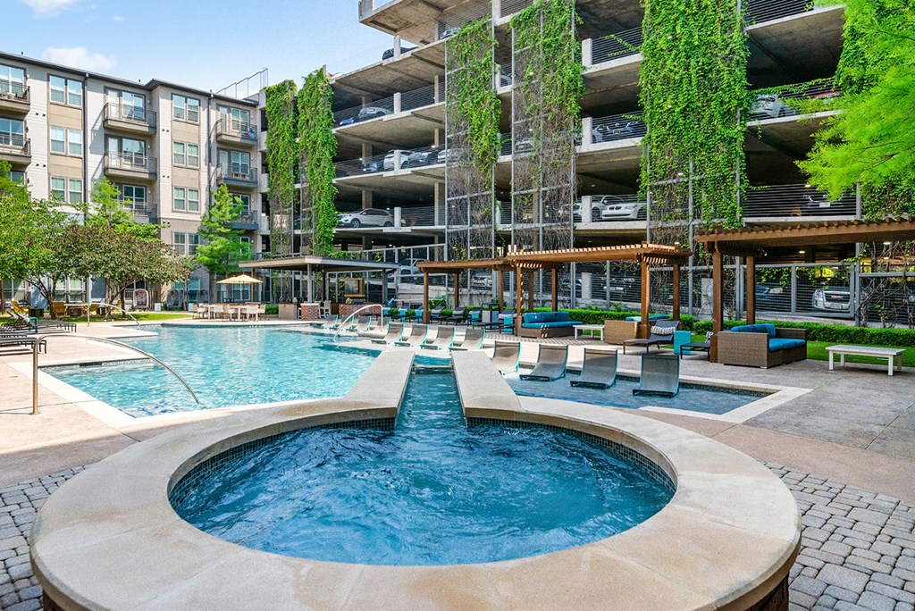 A large outdoor pool with a fountain in the middle of it.