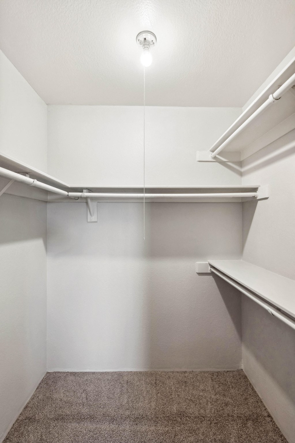 a walk in closet with white walls and a ceiling light