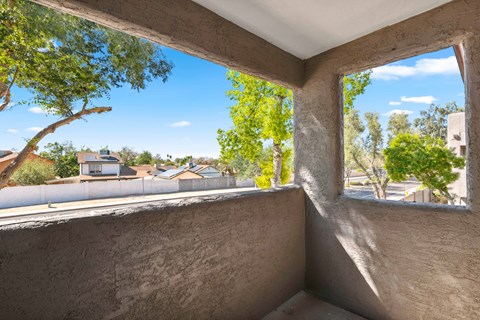 a large window on a balcony with a view of trees and houses