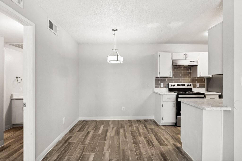 an empty kitchen with white appliances and a wood floor