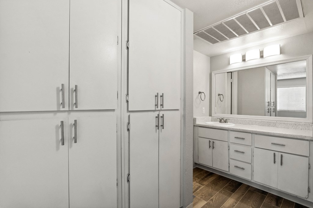 a bathroom with white cabinets and a sink and a mirror