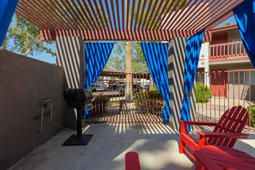a patio with red chairs and blue and white curtains