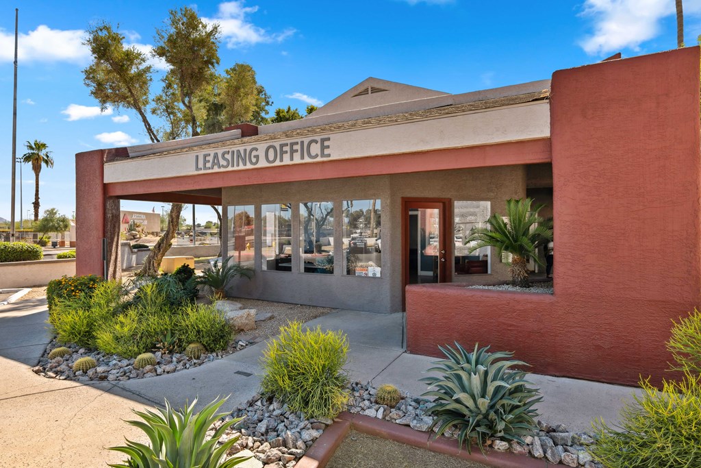 the front of the leasing office of a building with plants