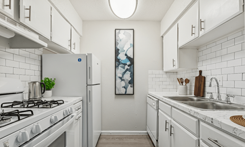 A kitchen with white cabinets and a white gas stove.