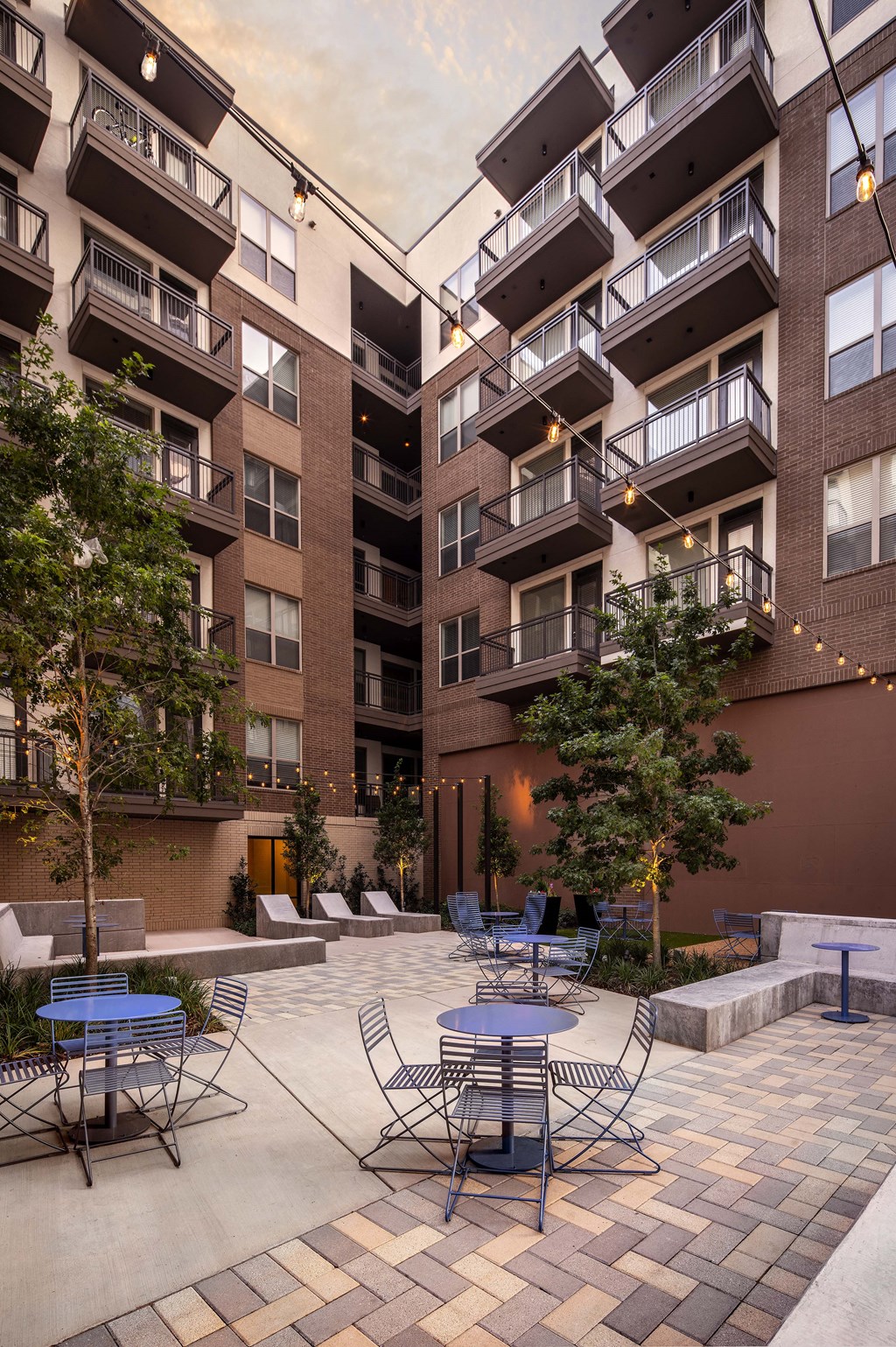 a courtyard with tables and chairs and an apartment building in the background