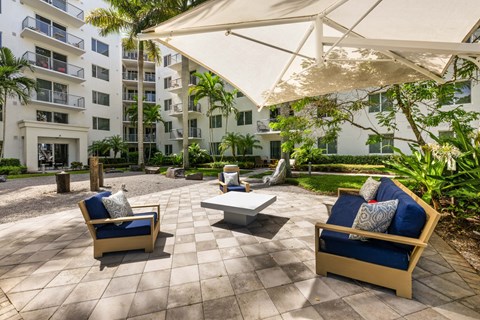 a patio with chairs and an umbrella in front of an apartment building