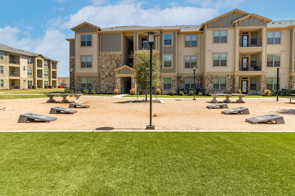 a picnic area with benches and a lamppost in front of an apartment building