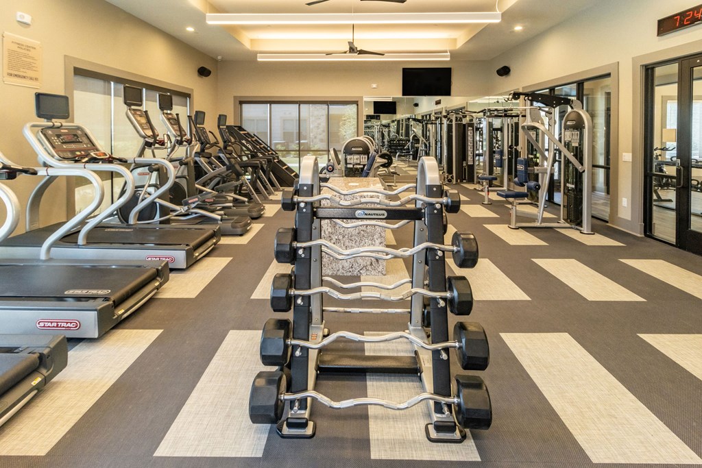 a large fitness room with cardio equipment and weights