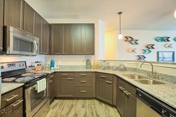 A kitchen with brown cabinets and a granite counter top.