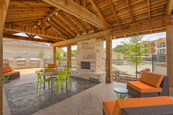 A patio with a fireplace and chairs.