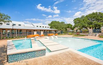 A swimming pool with a waterfall and a building in the background.
