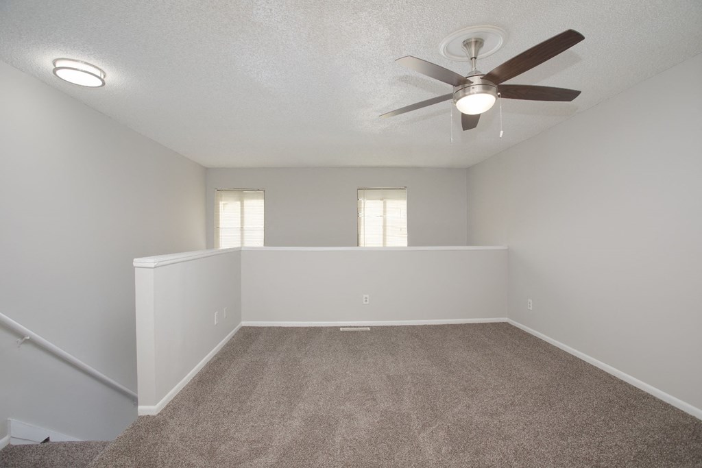 a large empty room with a ceiling fan