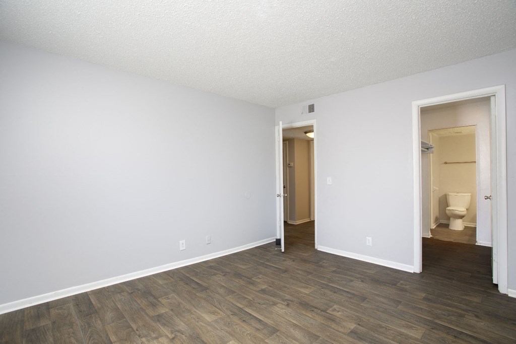 a bedroom with a hardwood floor and white walls