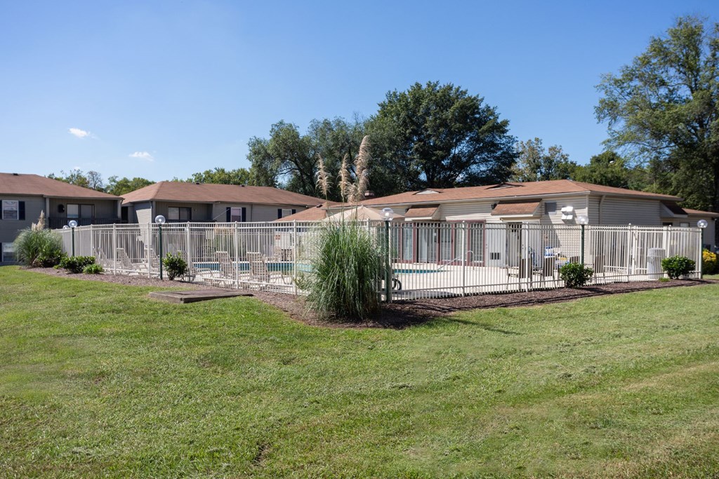 an fenced in swimming pool in front of a row of condominiums