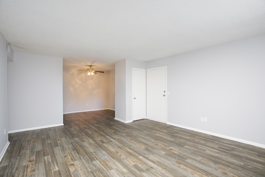 an empty living room with hardwood floors and a ceiling fan